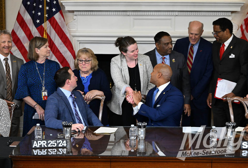 Molly at a bill signing supporting the University of Maryland shaking hands with Governor Wes Moore and Senate President Bill Ferguson